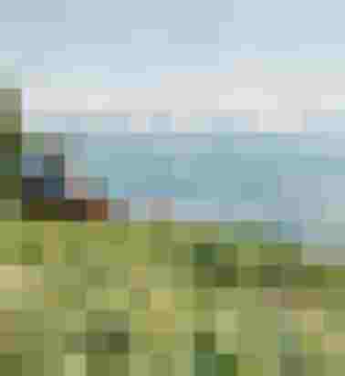 Zwei Wandernde sitzen auf einer Bank mit Blick über ein Tal und eine Bergkette