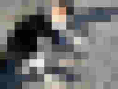 Katze liegt entspannt auf Steinboden, umgeben von einer blühenden Gartenlandschaft.