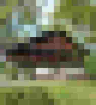 Hinterburghof mit Holzfassade, blumengeschmückten Balkonen, Sitzplatz und Wiese unter alten Bäumen